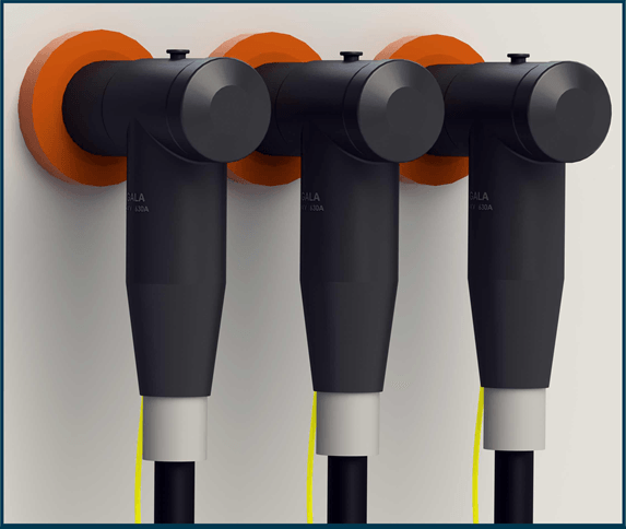 Three black elbow screened separable connectors plugged onto orange type C bushings on a panel wall, cable tails hanging below with yellow earth leads